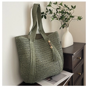 Detail of sage green woven tote bag with wooden bead tassels for summer vacation
