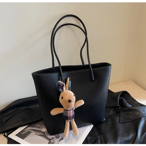 Close-up of black lychee grain leather tote bag with a cute plaid bunny charm