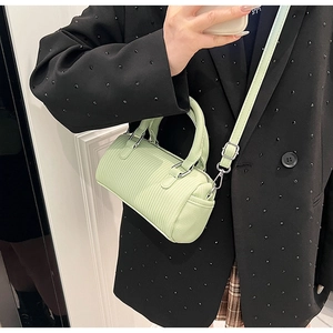 Detail of light green cylindrical crossbody bag with vertical ribbed texture and silver hardware