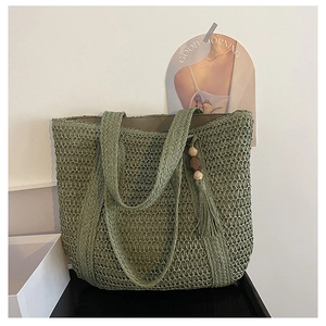 Detail of green woven tote bag showing texture, wooden bead charm and cotton tassel