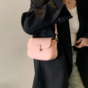 Pink lychee texture crossbody bag with gold buckle worn over a black blazer for women