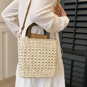 Beige woven straw tote bag with dark wood handles and a white drawstring liner