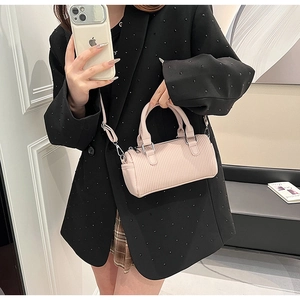 Chic pink pleated cylindrical handbag with silver hardware shown in lifestyle setting