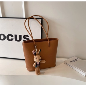 Detail of brown litchi pattern leather tote bag with a cute plush rabbit pendant