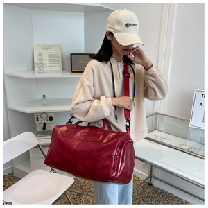 Detail showing the glossy red PU travel bag with adjustable strap for short trips