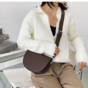 Detail shot of a dark brown matte leather saddle bag worn with an elegant winter outfit