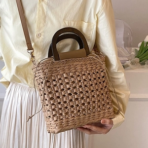 Handwoven straw tote bag with wooden handles and leather strap for summer beach holidays