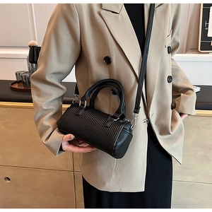 Close-up of black pleated cylindrical bag with dual handles and silver metal hardware details