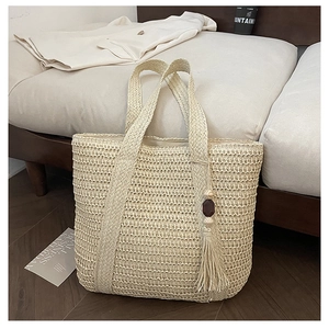 Close-up of beige woven tote bag with intricate knit texture and tassel wood bead charm