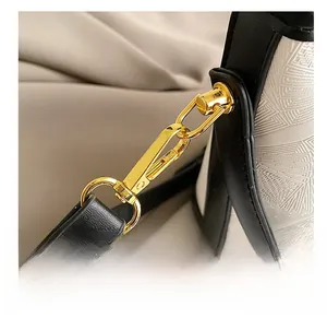Detail of high-quality gold hardware on a black and white bucket bag with embossed texture