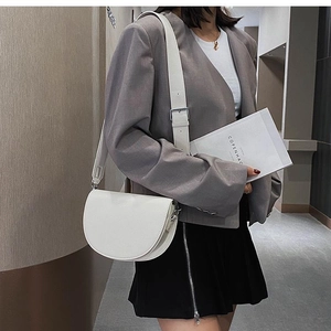 Minimalist white semi-circle crossbody bag with silver hardware on a female model