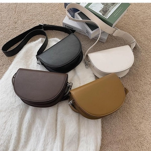 Flat lay of textured matte leather saddle bags in four colors on a cozy carpet