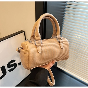 Detail of camel cylindrical bag with pleated leather texture and silver rings