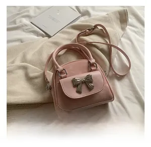 Detailed view of a pink quilted bucket bag with a metal bow on a soft fabric base