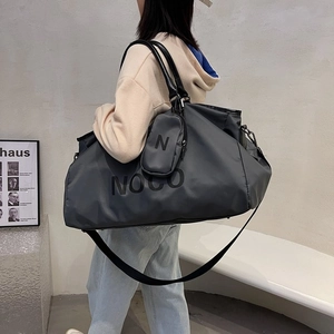 Large dark grey nylon travel tote bag with shoulder strap and mini pouch shown on model