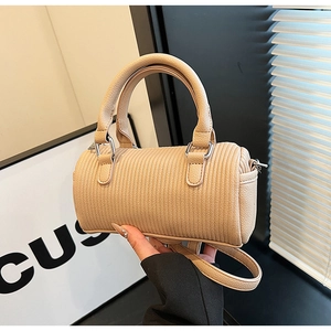Close-up of beige cylindrical pillow bag with vertical striped texture and top handles
