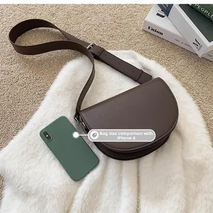 Deep brown saddle bag with adjustable strap and smartphone for size comparison