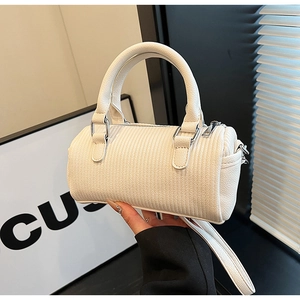 Detail of white cylinder bucket bag showing lychee grain leather and silver hardware