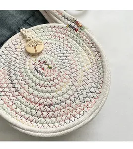 Detail of round woven straw bag featuring colorful zigzag stitching and wooden button