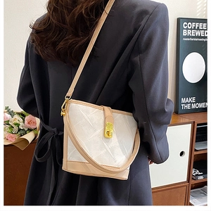 Detail of trendy bucket bag with textured beige leather and gold twist-lock closure
