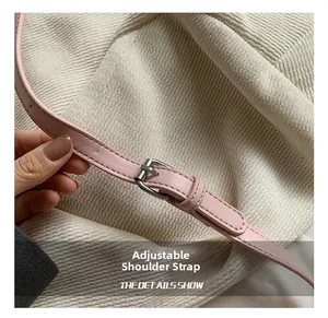 Detail showing the adjustable pink leather strap with a silver metal buckle on a bucket bag