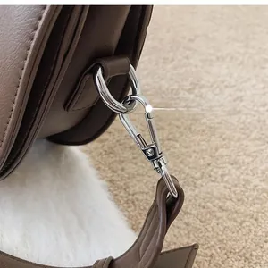 Detailed close-up of premium silver metal buckle on a dark brown textured leather handbag