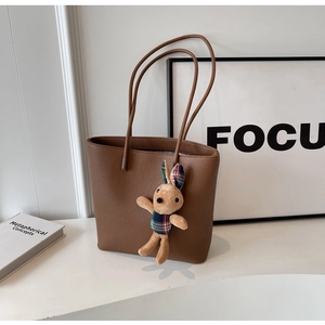 Detailed view of a brown pebbled leather tote bag with a cute plush bunny pendant accessory
