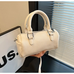 Detailed view of a white barrel bag with vertical texture and silver metal hardware