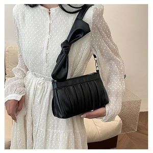 Primo piano della borsa a tracolla nera a pieghe con un grande fiocco decorativo sulla tracolla