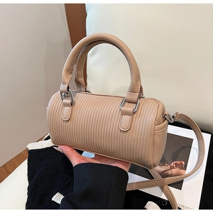 Detail of beige cylinder handbag featuring vertical striped leather and silver hardware