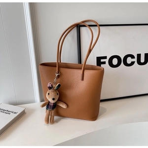 Detailed shot of brown pebbled leather tote bag with a cute plaid bunny keychain