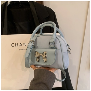 Detail of light blue mini bucket bag with gold bow clasp and elegant round handles