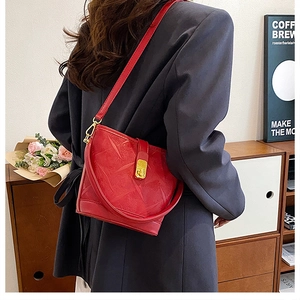 Detail view of red embossed leather bucket bag featuring a vintage golden metal twist lock