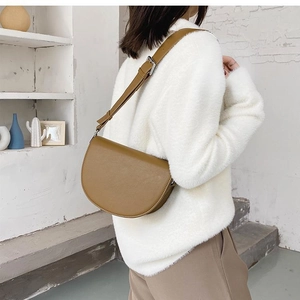 Modern brown leather saddle bag shown on model for realistic scale and shoulder fit