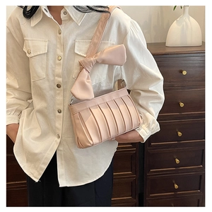 Dettaglio della borsa sottobraccio plissettata rosa chiaro con fiocco decorativo in pelle