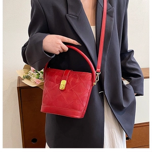 Detail of red bucket bag showing geometric texture and golden rectangular lock buckle