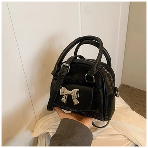 Detail of black glitter texture bag with silver bow accent and zipper closure