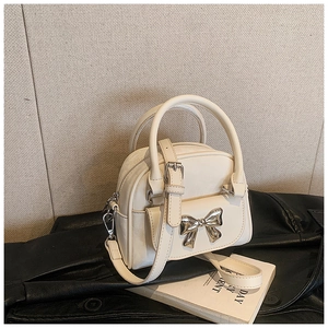 Close-up of beige quilted bucket bag with silver bow buckle and dual handles