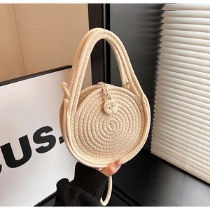 Close-up of woven mini straw bag featuring round wood button and intricate rope texture