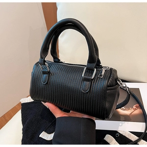 Detail of black pleated barrel bag with pebbled leather accents and silver hardware