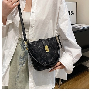 Detailed view of black bucket bag featuring 3D embossed texture and gold metal hardware
