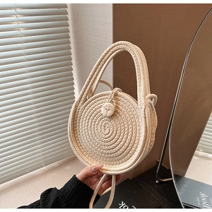Close-up of woven straw round mini bag with decorative wood button and dual handles
