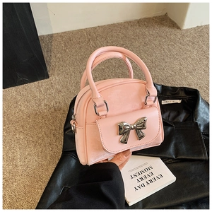 Detailed close-up of light pink leather handbag with silver metallic bow and top handles