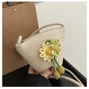 Detail of hand-woven bucket bag with yellow floral charms and cream woven texture