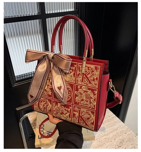 Detail of red wedding tote bag with gold floral embroidery and a striped bow charm