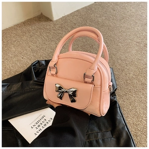 Detailed shot of pink quilted handbag featuring a silver bow buckle and dual handles