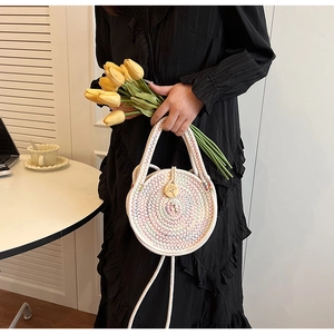 Macro detail of a hand-woven white round straw bag with colorful stitching and wooden button