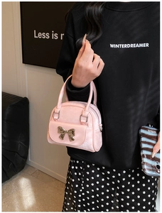 Close-up of pink leather handbag with a golden metal bow and elegant top handles