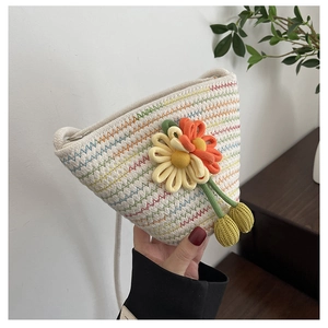 Macro shot of hand-woven straw bucket bag with 3D floral accents and rainbow stitching