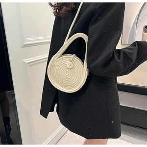 Detailed texture of hand-woven cream mini round straw bag with circular buckle and strap
